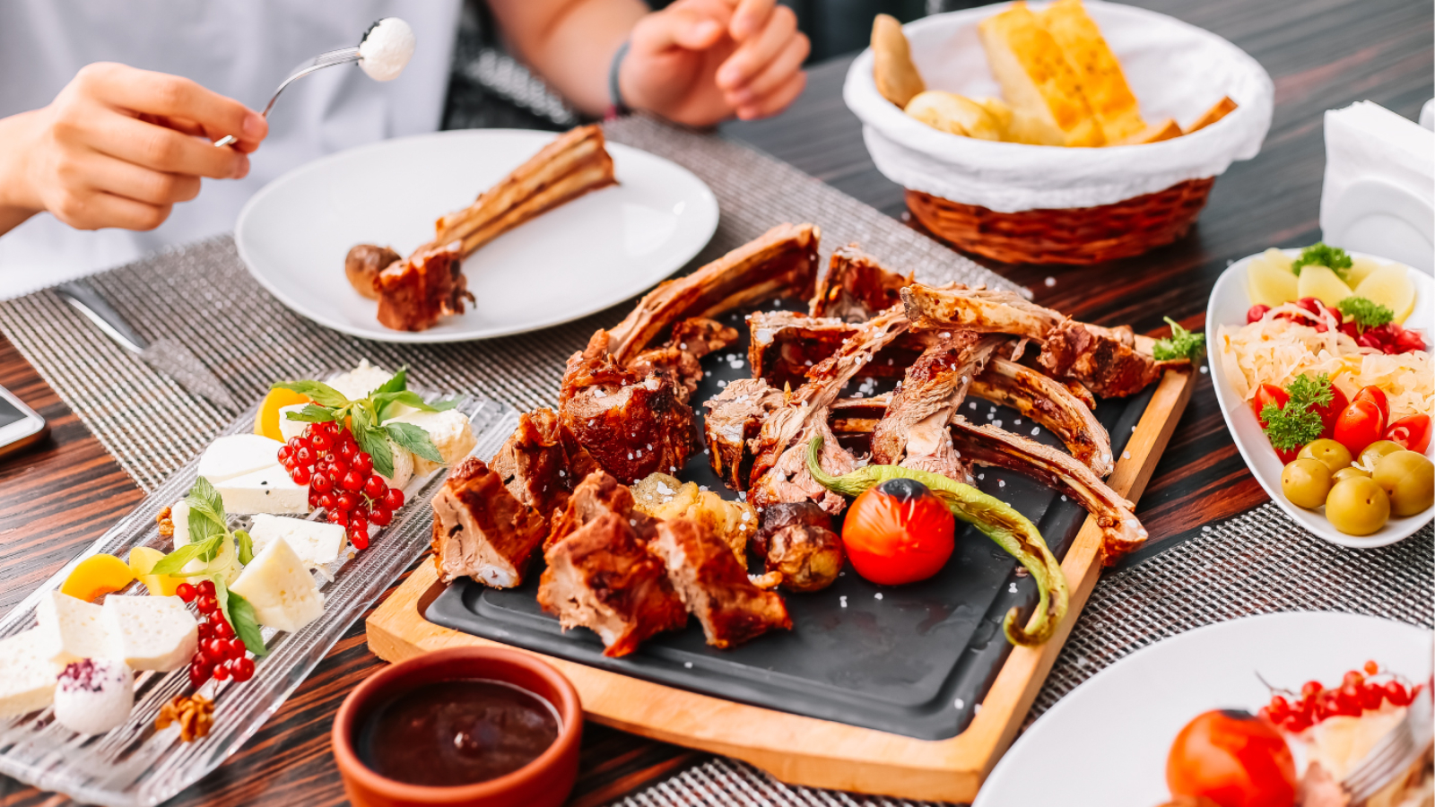 man-eats-grilled-sliced-lamb-wooden-board-potato-tomato-pepper-pickles-cheese-side-view